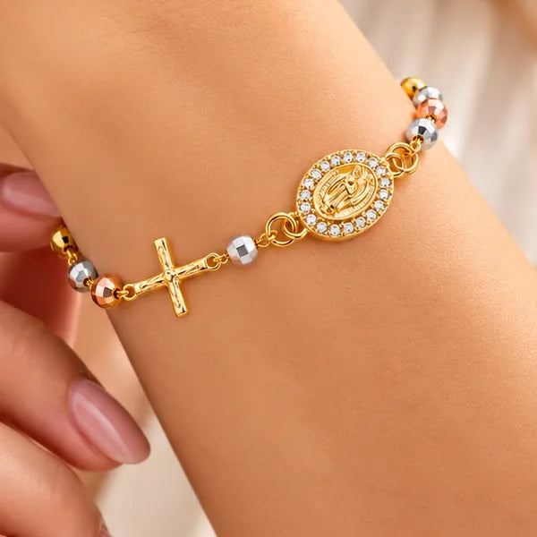 Detalle de la pulsera rosario: medalla ovalada de la Virgen María con borde de pequeñas piedras, cruz y cuentas tricolor
